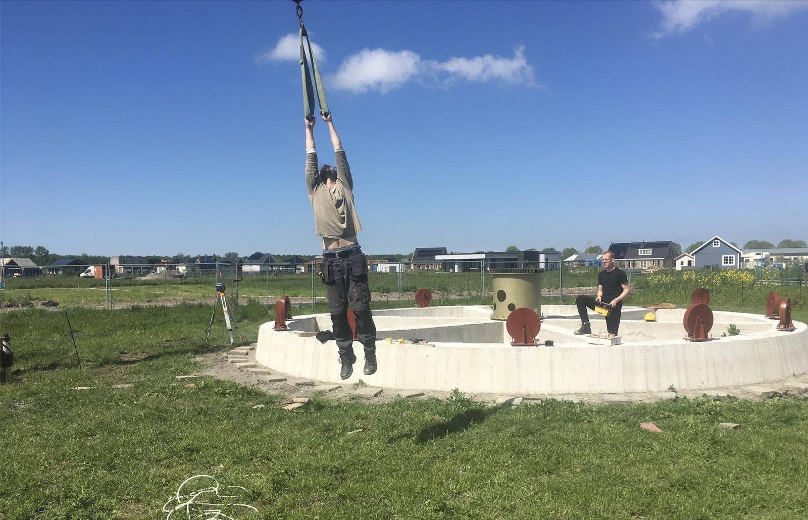 Hangend aan de kraanhaak boven de betonnen ring